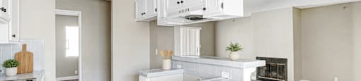 A kitchen with white cabinets and a wooden floor.