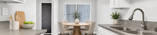 A modern kitchen with white cabinets and a dining area with a table and chairs.