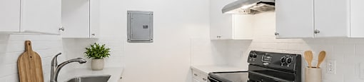A kitchen with white cabinets and a black stove top oven.