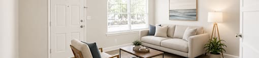 A living room with a white couch, a wooden chair, and a coffee table.
