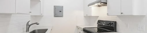 A kitchen with white cabinets and a black stove top oven.