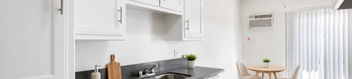 A kitchen with white cabinets and a black stove top oven.