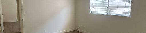A room with a window and wooden flooring.