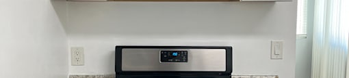 an empty kitchen with white cabinets and a stove and microwave