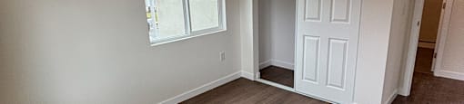 A room with wooden flooring and a white door.
