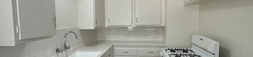 A clean, white kitchen with oven and range