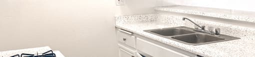 A kitchen with white cabinets and a stove top oven.