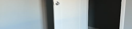 A white door is open in a room with wooden flooring.