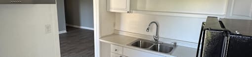 A kitchen with a black fridge and white cabinets.