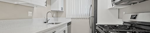 A kitchen with white cabinets and a black stove top oven.
