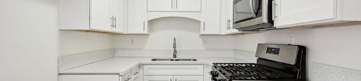 a white kitchen with white cabinets and a black stove
