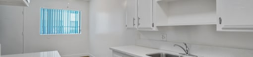 A modern kitchen with white cabinets and a stove top.