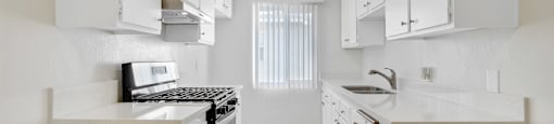 A kitchen with white cabinets and a wooden floor.