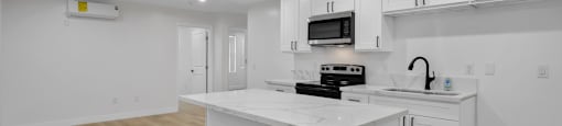 A kitchen with white cabinets and a countertop with a microwave and toaster oven on it.