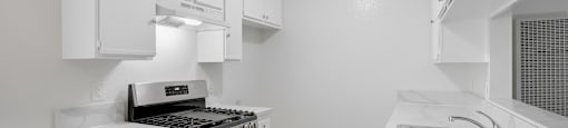 A kitchen with white cabinets and a stove top oven.