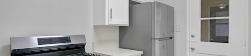 A kitchen with a stove, refrigerator, and cabinets.