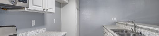 A kitchen with white cabinets and a white fridge.