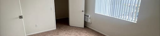 an empty room with a door to a closet and a window