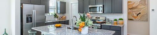 A kitchen with a granite countertop and green chairs.