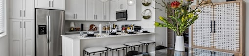 A modern kitchen with a glass table and white cabinets.