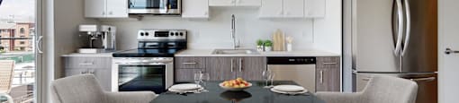A modern kitchen with a dining table set for two.