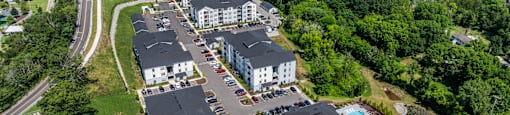 A bird's eye view of a residential area with houses, roads, and a parking lot.