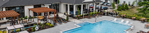 A large outdoor swimming pool surrounded by lounge chairs and umbrellas.