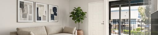 A living room with a beige couch, a wooden coffee table, and a plant.