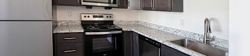 A kitchen with dark wood cabinets and a stainless steel refrigerator.