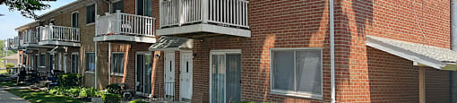 A red brick apartment building with a white railing on the balconies.