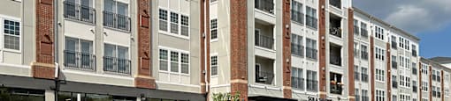 A row of apartment buildings with balconies and flower pots.