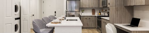 A modern kitchen with a white island and grey chairs.