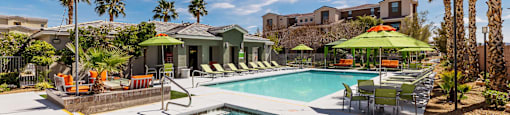 a swimming pool with chairs and umbrellas and a house in the background at EVERETT APARTMENT HOMES, Nevada