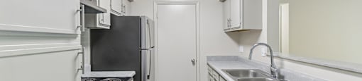 A kitchen with a black fridge and stove top oven.