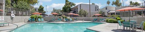 A large swimming pool with a sun lounger and umbrella.