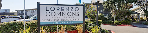 A sign for Lorenzo Commons apartments stands in front of a building.