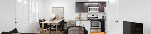 a living room and kitchen with white walls and hardwood floors