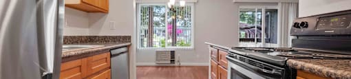 Apartments for Rent Santa Clara - Hidden Lake - Kitchen With Stainless Steel Appliances, Wood Cabinetry, Granite Style Countertops, Open Dining Area, And Sliding Glass Door.