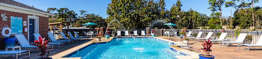 A swimming pool surrounded by lounge chairs and trees.