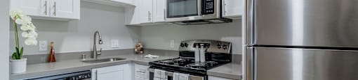 Two Bedroom Apartments in Hayward CA - Paseo Gardens - Modern Kitchen with Grey Countertops, White Cabinetry, Stainless Steel Appliances, and Wood Flooring