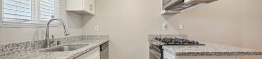 Fremont, CA, Apartments for Rent - Northgate Savoy - Kitchen with Granite Countertops, White Cabinetry, Stainless Steel Appliances, Tile Flooring, and a Large Window.