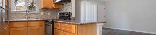 Apartments For Rent In Milpitas, CA - Spring Valley - Kitchen With Tile-Like Flooring, Wood-Inspired Cabinets, Microwave, Efficient Appliances, Granite Countertops, Tile Backsplash, And Dual Sink