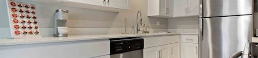 A kitchen with white cabinets and a stainless steel refrigerator.