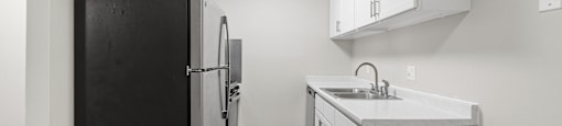 A kitchen with a black refrigerator and white cabinets.