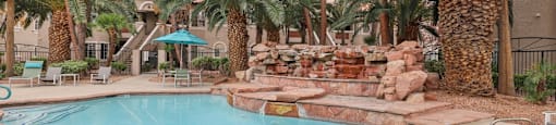 A pool surrounded by palm trees and rocks.