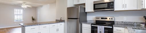 A kitchen with white cabinets and a wooden floor.