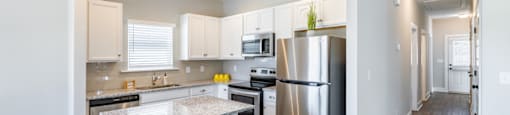 A modern kitchen with stainless steel appliances and wooden floors.