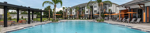 A large swimming pool with lounge chairs and a building in the background.