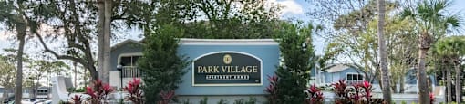 a sign that says park village with trees in the background