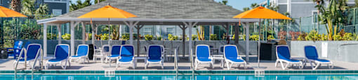 a swimming pool with blue chairs and yellow umbrellas
